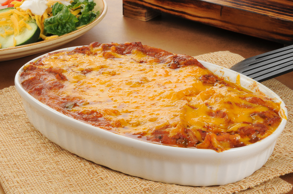 A chicken enchilada casserole topped with cheddar cheese